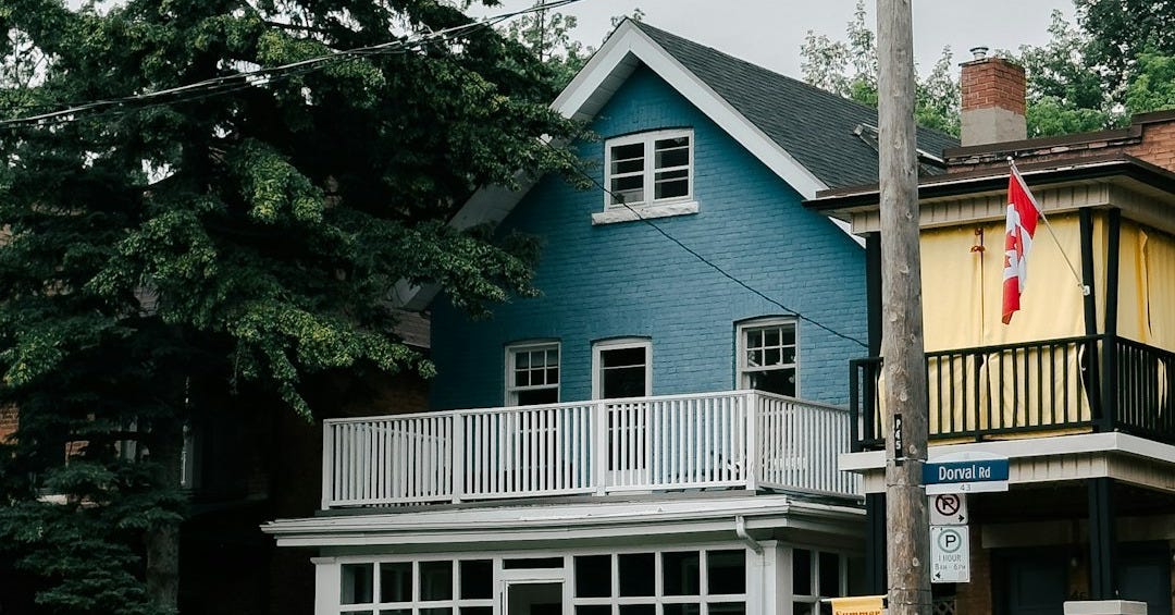 Two houses, one blue and one yellow, with canadian flag.