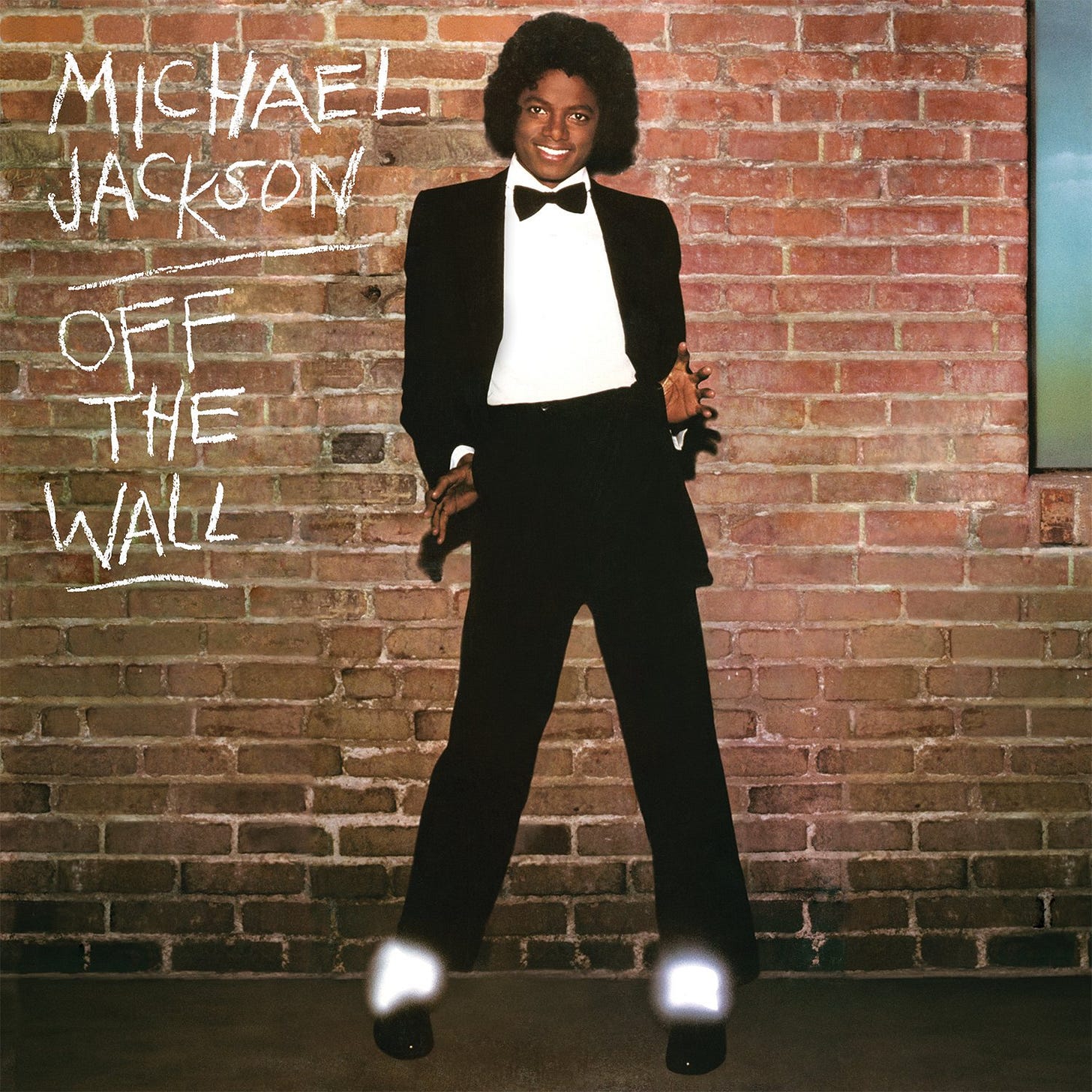 Album cover for OFF THE WALL featuring Michael Jackson in a black tuxedo and bow tie posing with jazz hands against a red brick wall. His white socks are glowing. Beside him is text for the album title and artist written uppercase letters in chalk. 