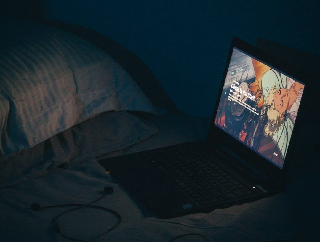 black laptop computer turned on on bed black laptop computer turned on on bed