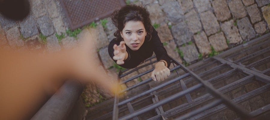 Woman climbing ladder reaching for a hand