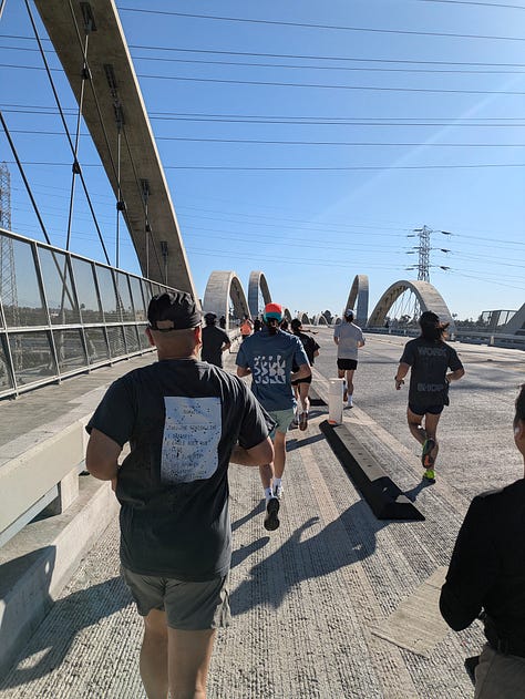 A photo of people running across the 6th St Bridge, past the old American Apparel building, and my tshirt saying EAT PASTA RUN FASTA