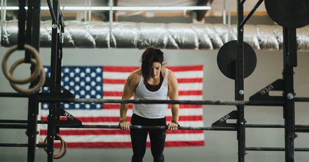 woman in gray tank top and black pants standing on red and black exercise equipment