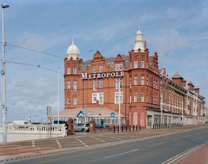 Red brick Metropole hotel with towers beside a seafront road