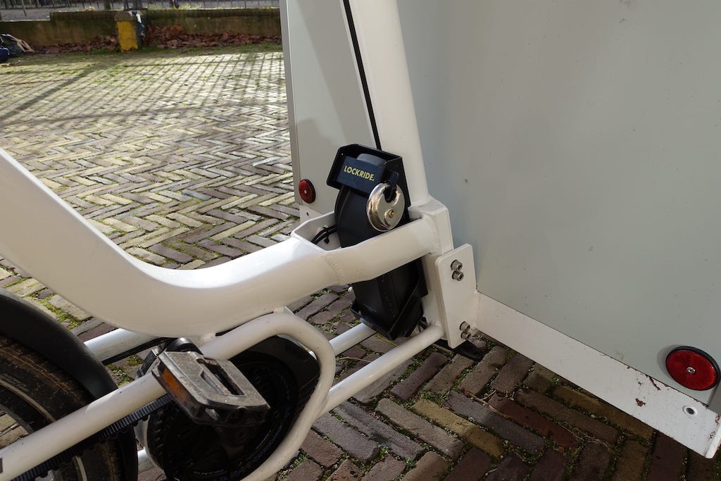 The battery for the bike is about the size of a large carton of milk. It sits on the back of the box on the cargobike. This battery has an extra lock. 