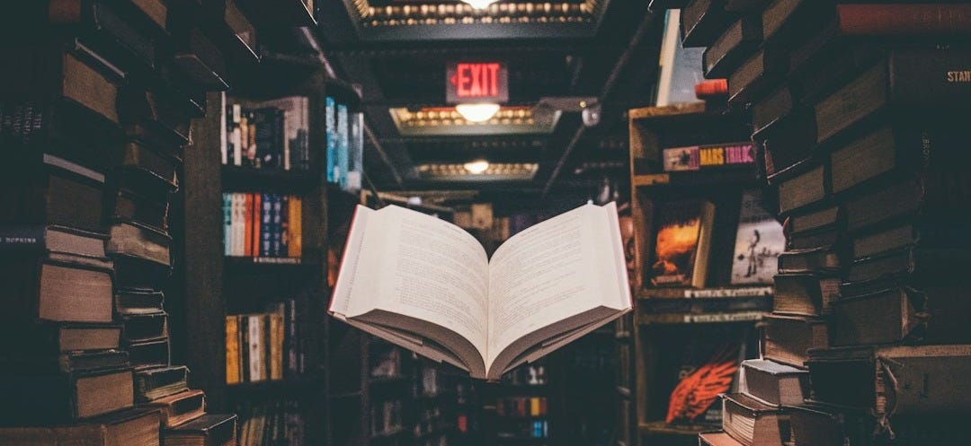 view of floating open book from stacked books in library