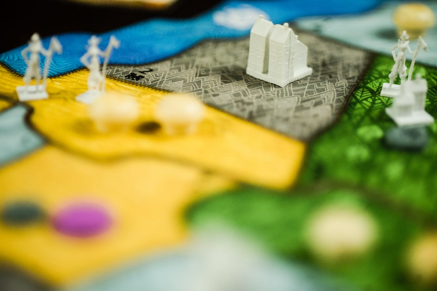 Invader pieces from the game Spirit Island in focus on the game board. In the foreground are player pieces and board pieces.