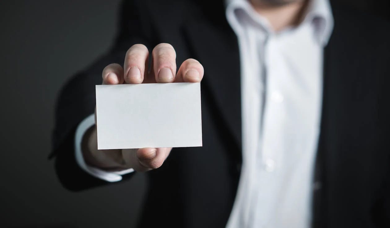 Pexels image by Pixabay of a man in a suit holding up a blank business card. Pexels image by Pixabay of a man in a suit holding up a blank business card.