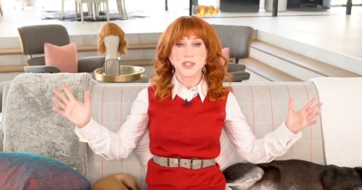 Comedian Kathy Griffin sits on a couch in a stylish living room, gesturing animatedly while wearing a red dress and white blouse. Comedian Kathy Griffin sits on a couch in a stylish living room, gesturing animatedly while wearing a red dress and white blouse.