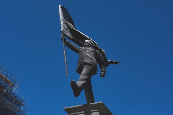 A statue of a man holding a flag covering his face. A statue of a man holding a flag covering his face.