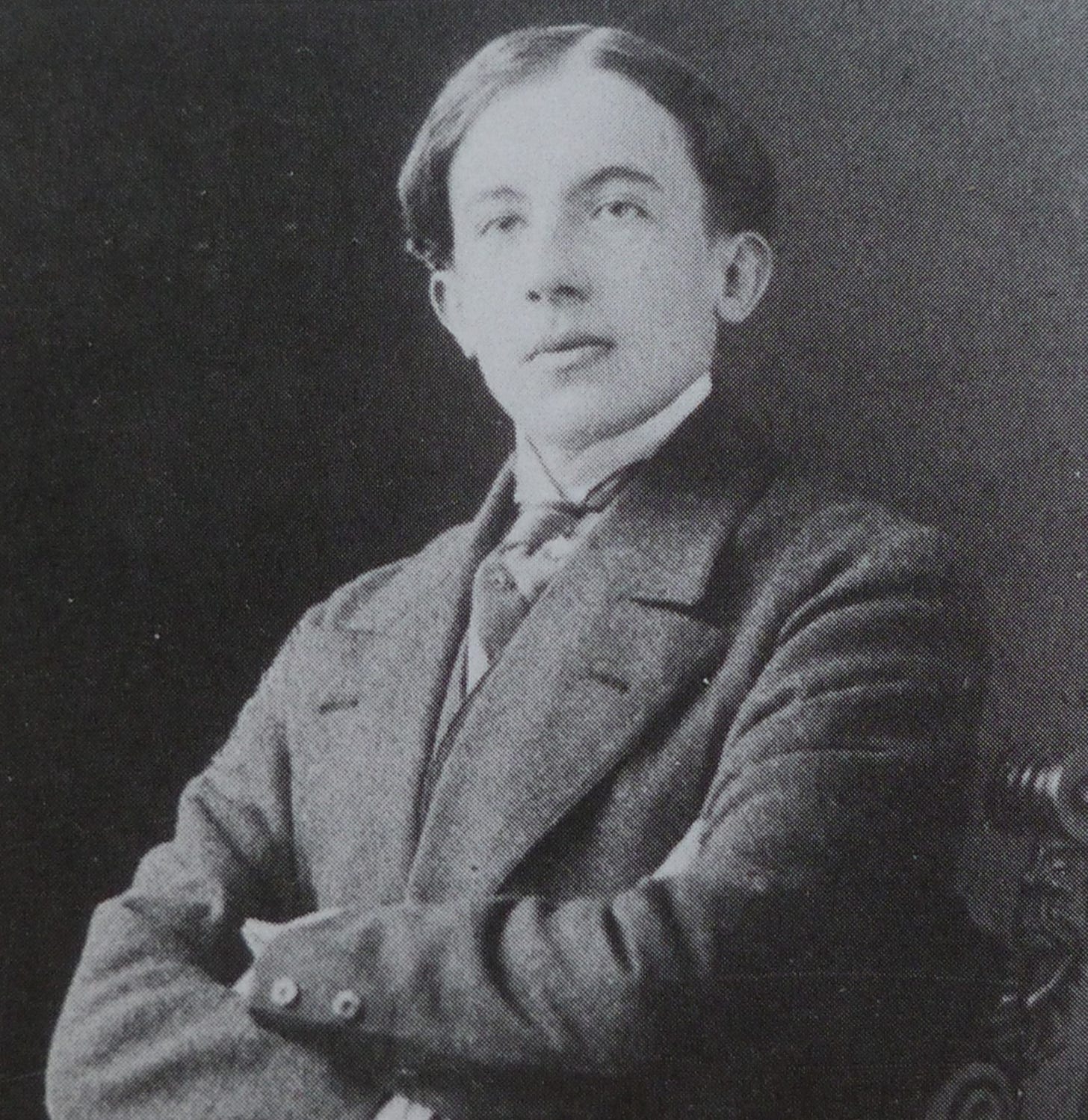 A young man in a dark suit with his arms folded. A young man in a dark suit with his arms folded.