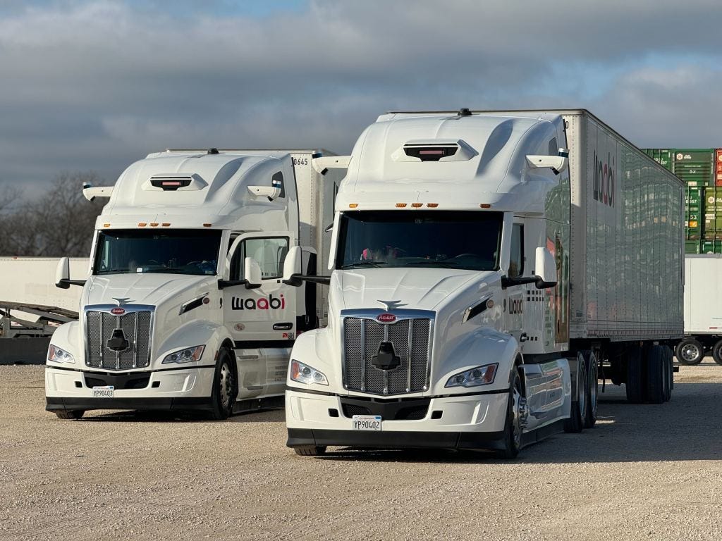 Front facing photo of two white Peterbilt heavy duty trucks with Waabi logo and branding.