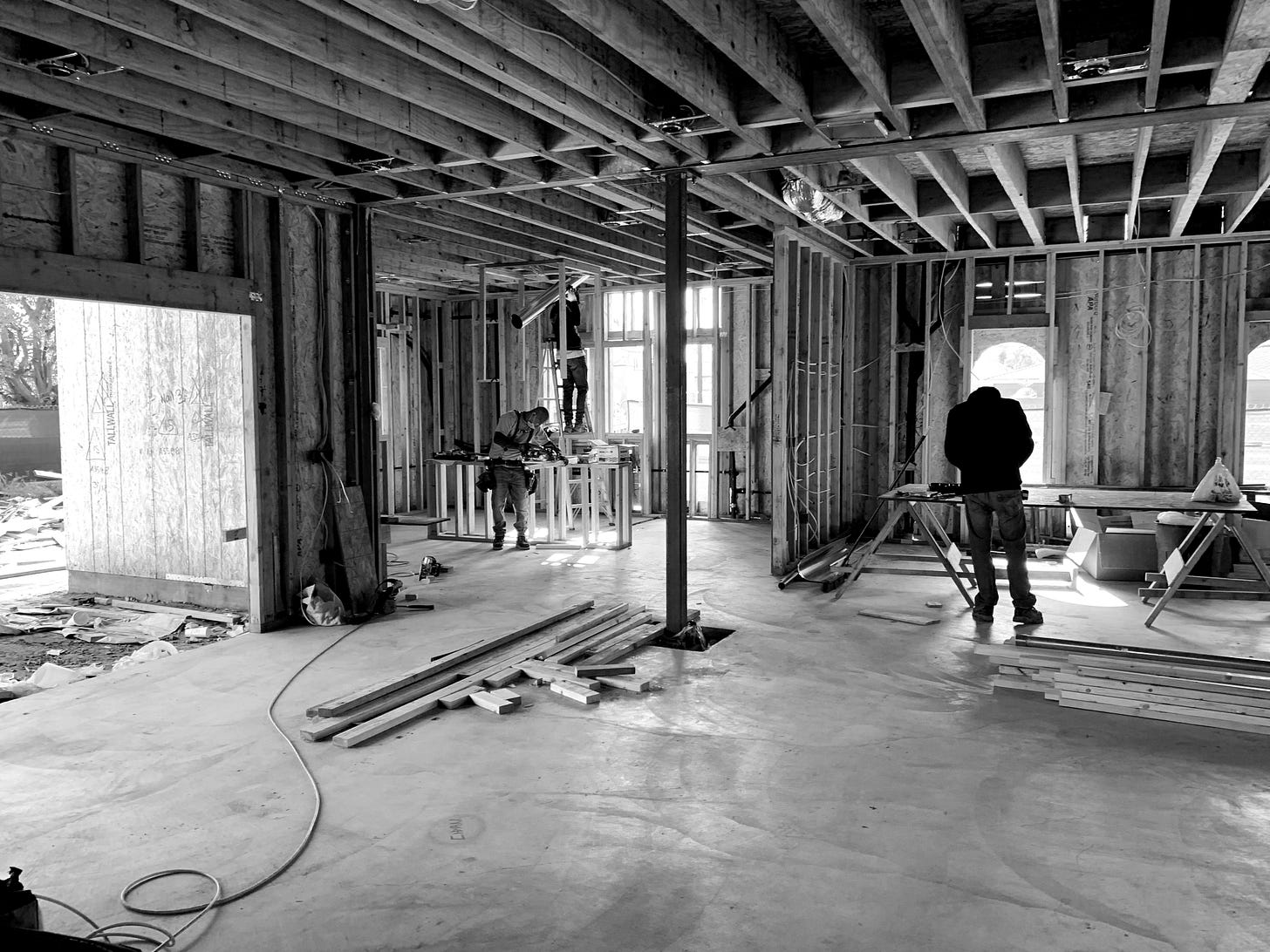 Two workers inside of a house under construction working to cut studs.
