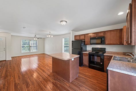 Exterior photos of new townhouses from the street and from the backyard. Several interior photos of a first floor with an open layout.