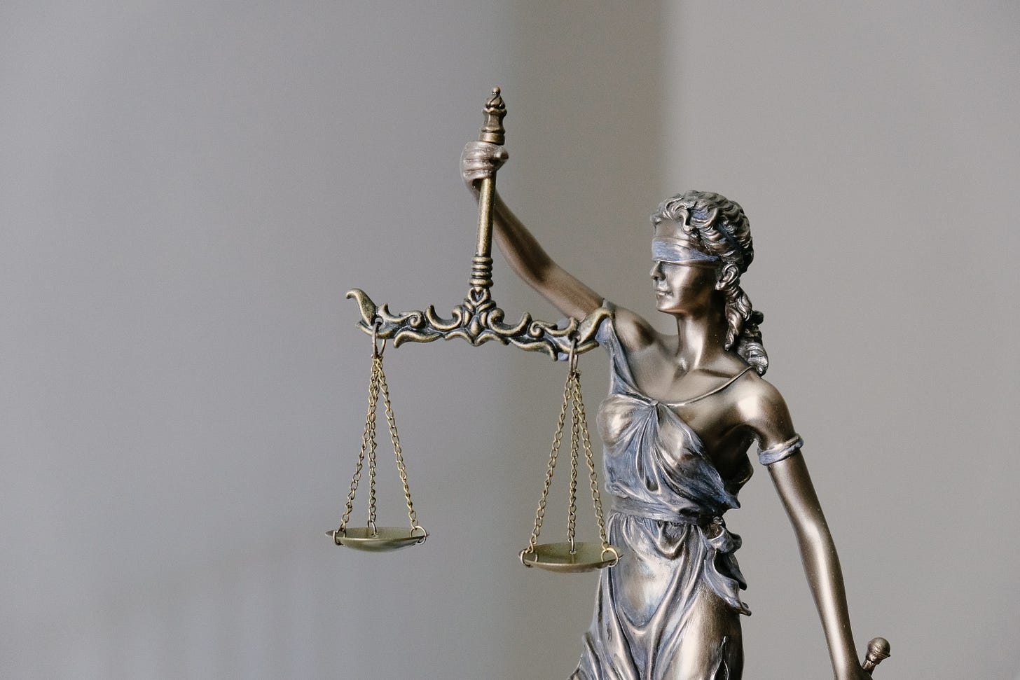 A photo of a small bronze statue of Justice in traditional garb, carrying a set of scales