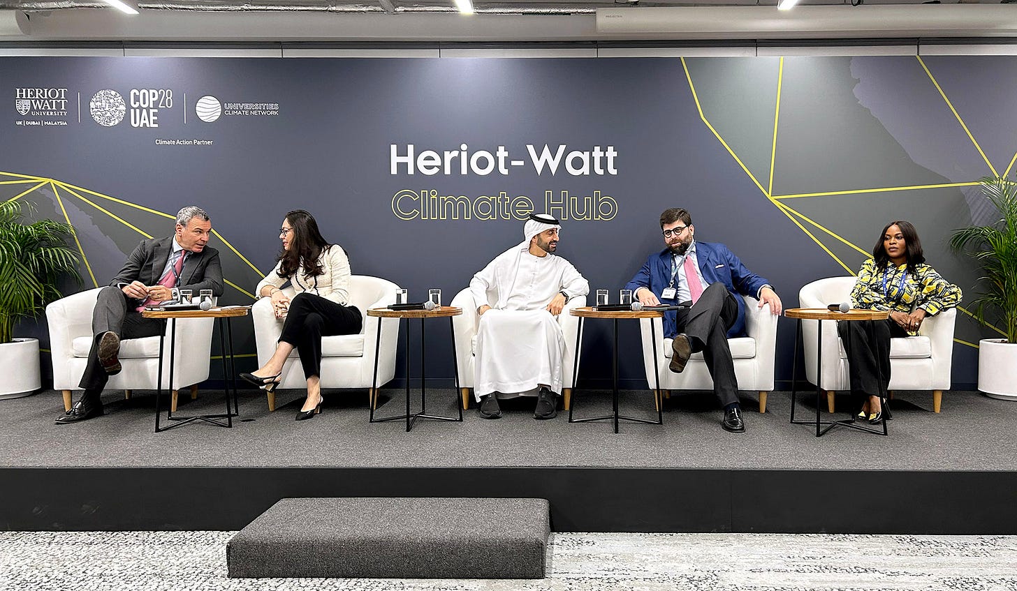 People sitting on a stage in front of a sign saying Heriot-Watt Climate Hub