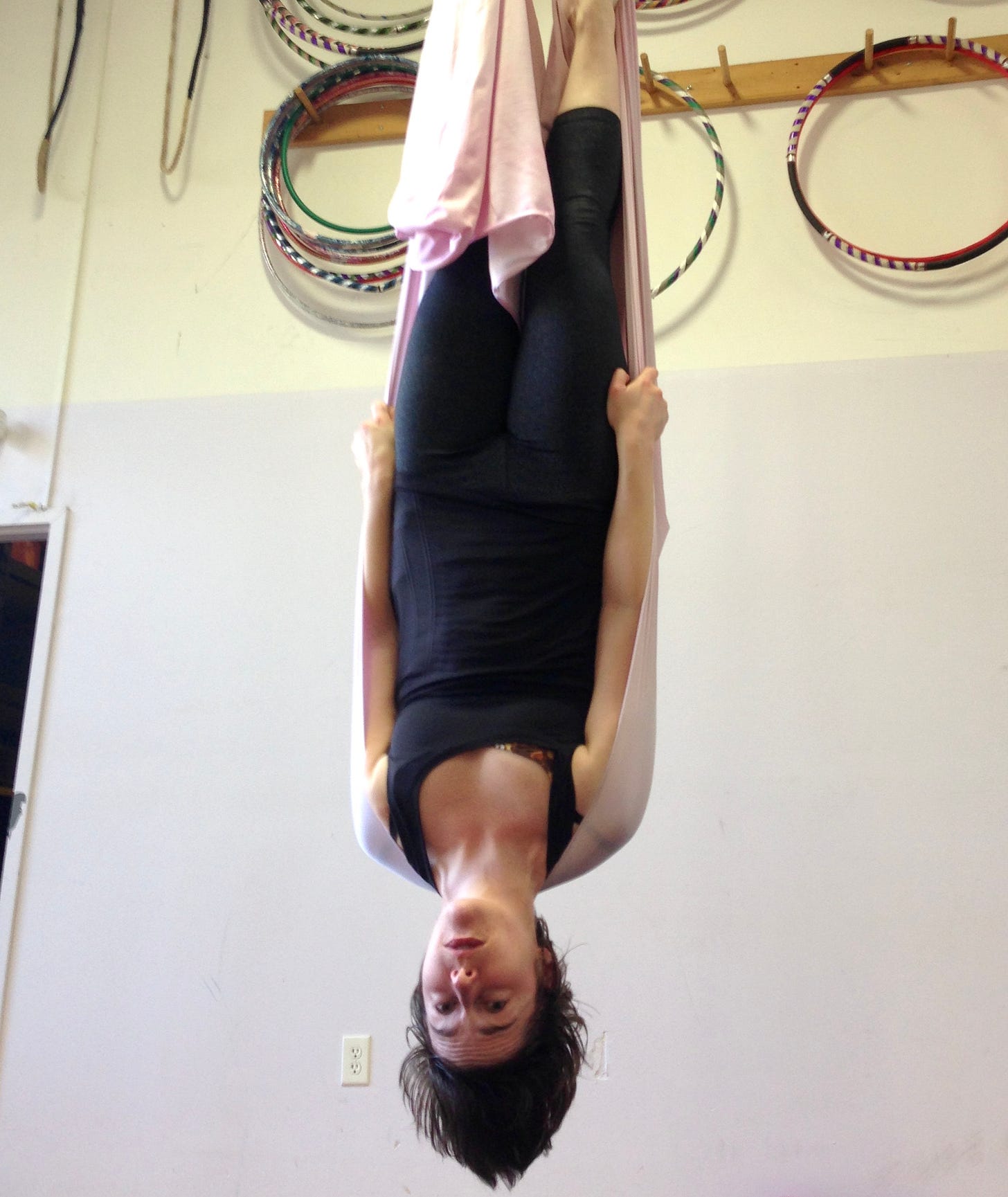 the author, suspended upside down in a pink arial silk at a circus school circa 2018