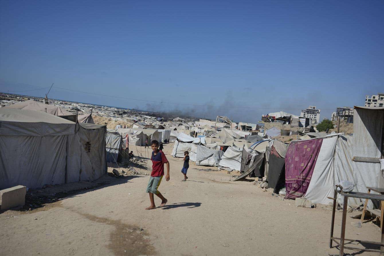 Boys standing among tents in Gaza Gity