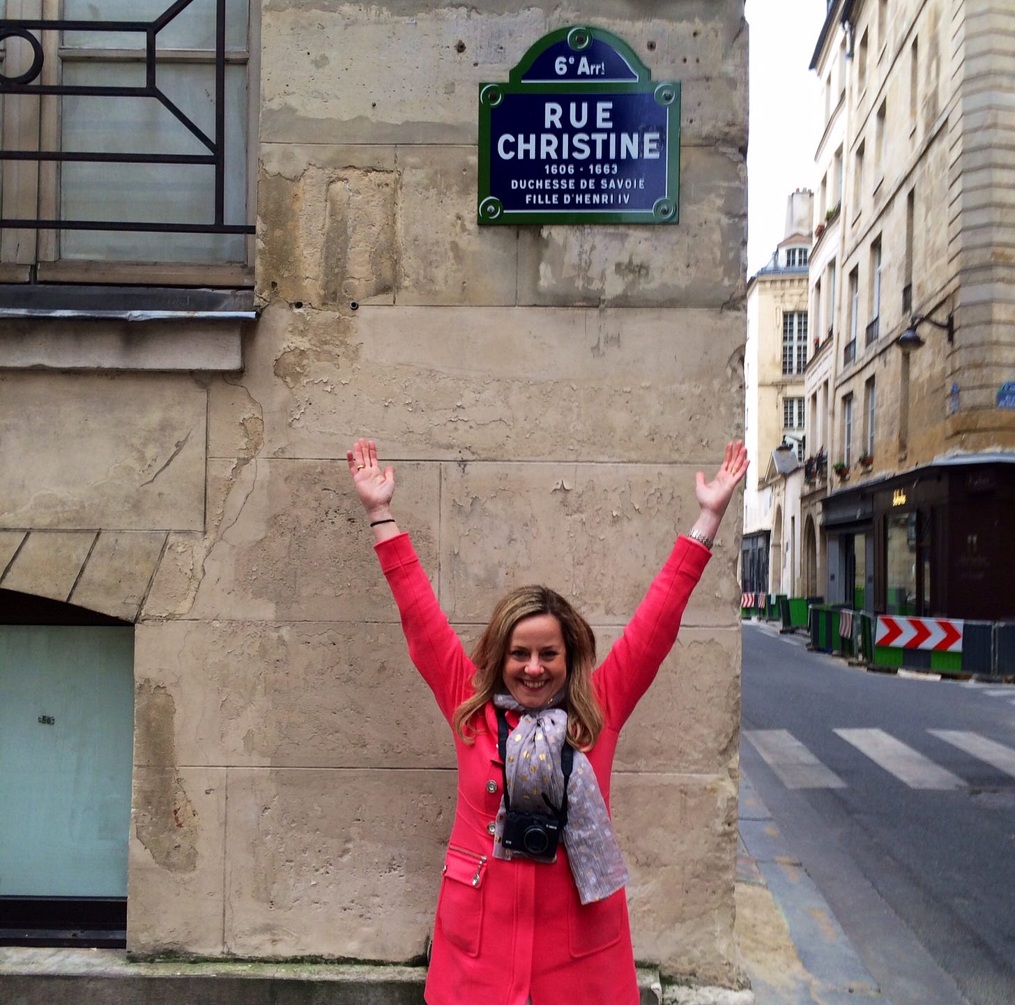 Memoir coach and developmental editor Christine Wolf in Paris, wearing a salmon colored coat and polka-dot scarf