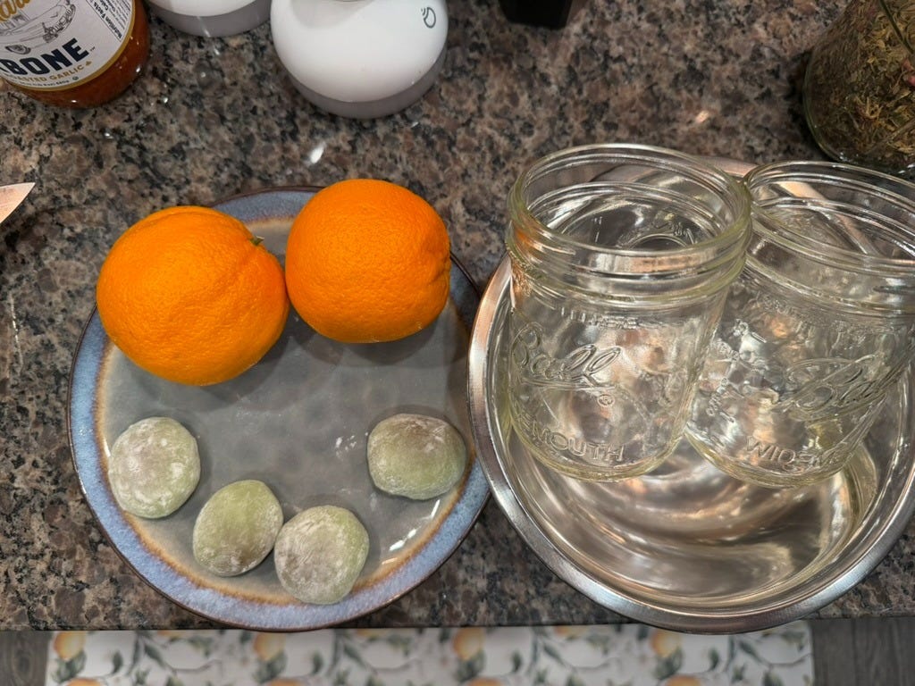 Photo: Silver bowls, small mason jars, oranges and mochi on plates.