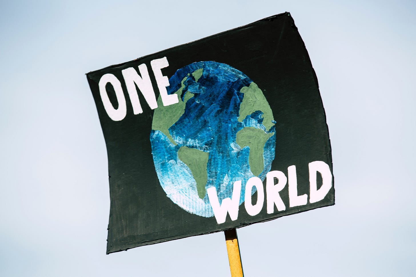 A placard with a drawing of the earth and "one world" written on it A placard with a drawing of the earth and "one world" written on it
