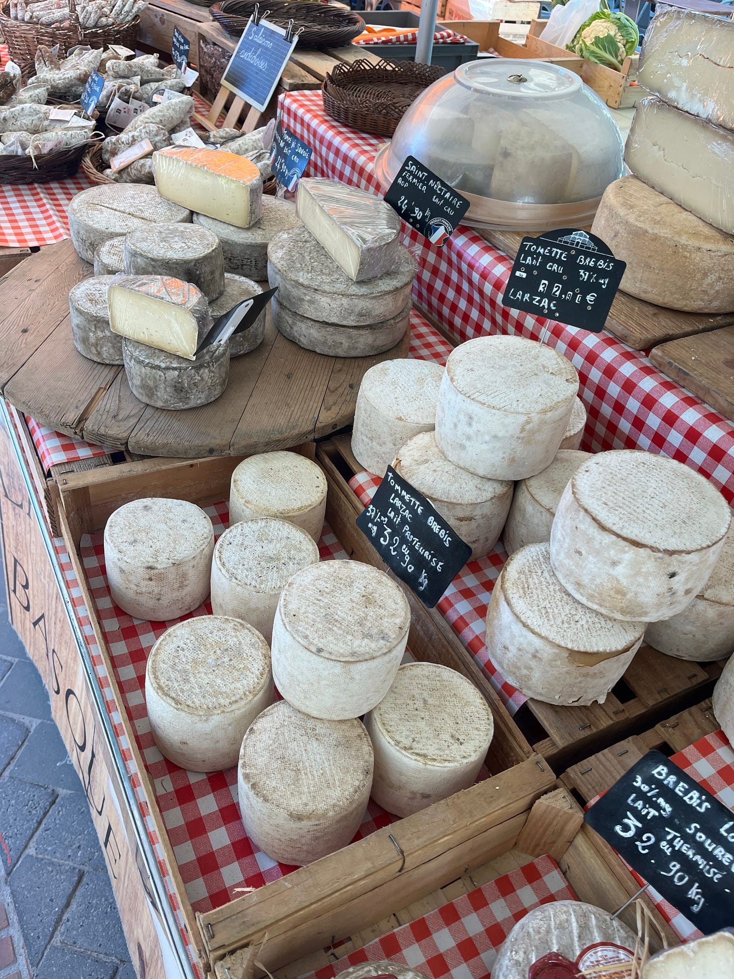 An array of French cheeses on display at an outdoor market.