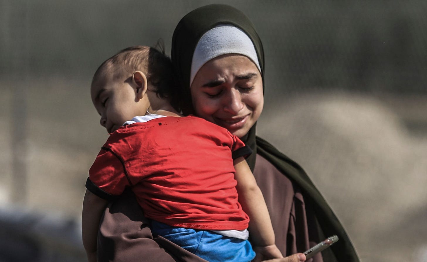 A young Palastinian woman reduced to tears carries her small child.
