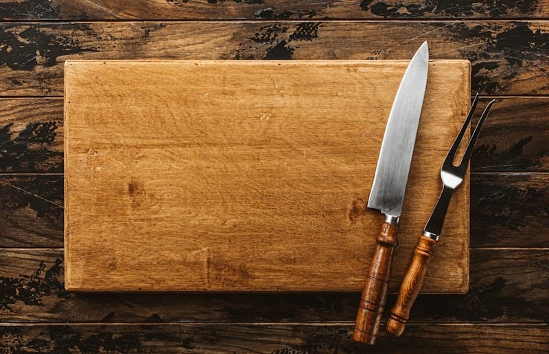 a knife and a board on a wooden surface