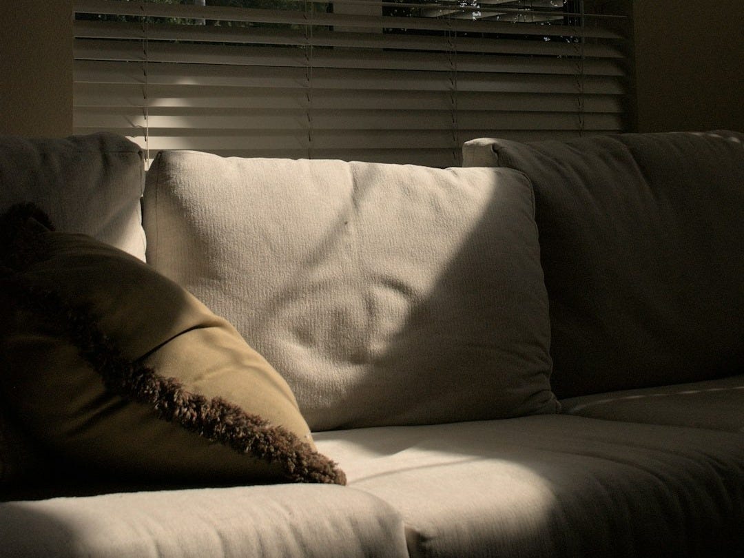 A white couch sitting under a window in a living room