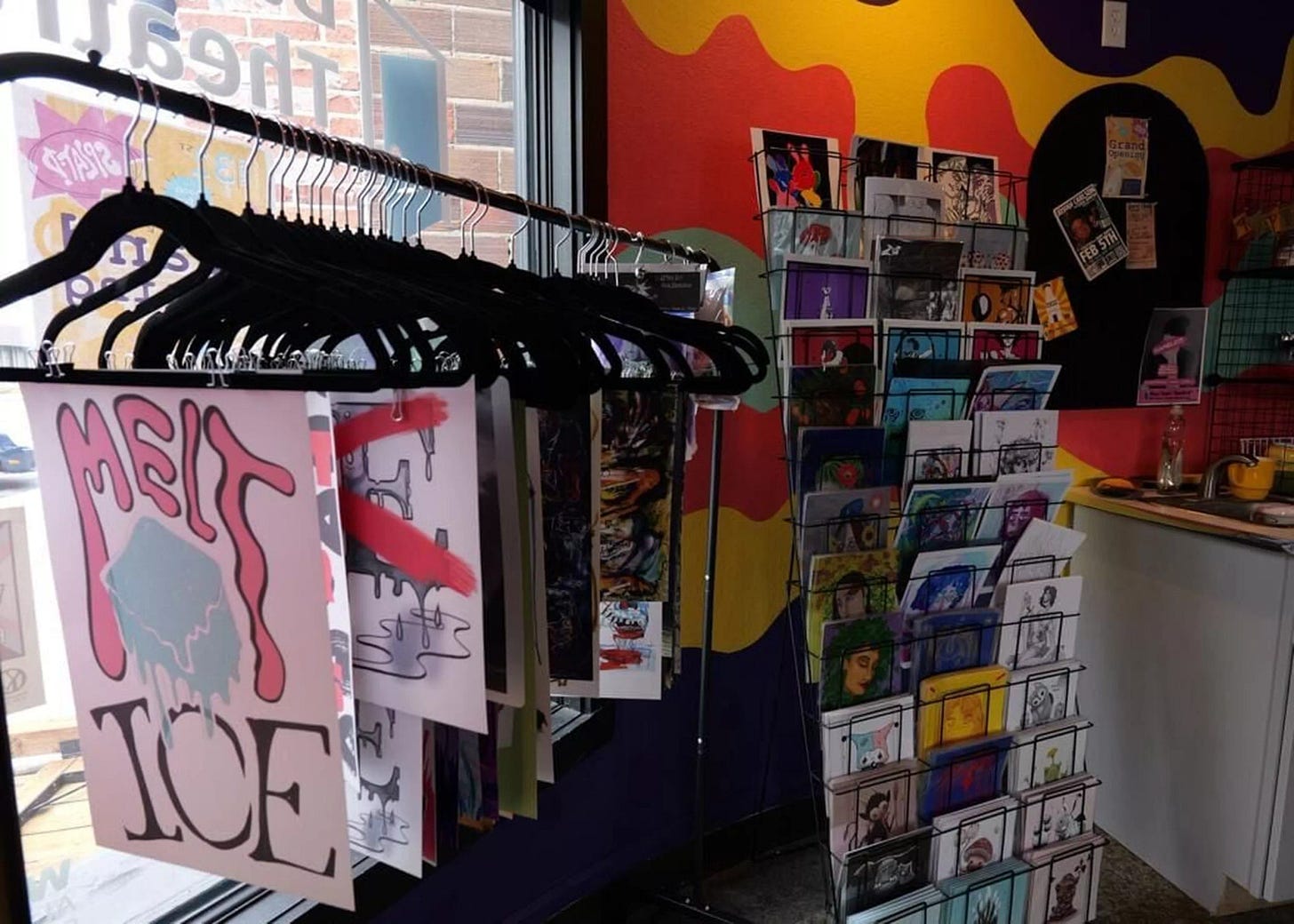 Display of prints and zines on racks inside a colorful shop with bold painted walls. Display of prints and zines on racks inside a colorful shop with bold painted walls.
