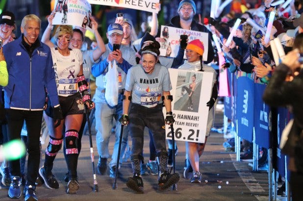 Hannah Gavios crosses the finish line of the New York City Marathon surrounded by supporters.