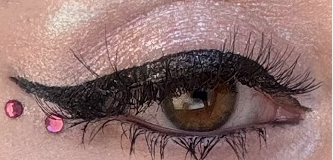 Extreme close-up of a graphic winged eyeliner look with pink rhinestones, created using Half Magic Magic Flik and Glitterpuck Extreme close-up of a graphic winged eyeliner look with pink rhinestones, created using Half Magic Magic Flik and Glitterpuck