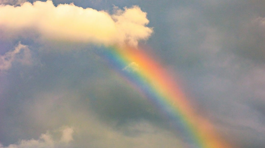 a rainbow in the sky with clouds in the background