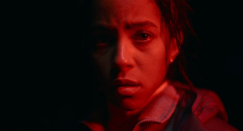 A still from the movie "Passenger." Actress Lou Llobell stands in a red light. 