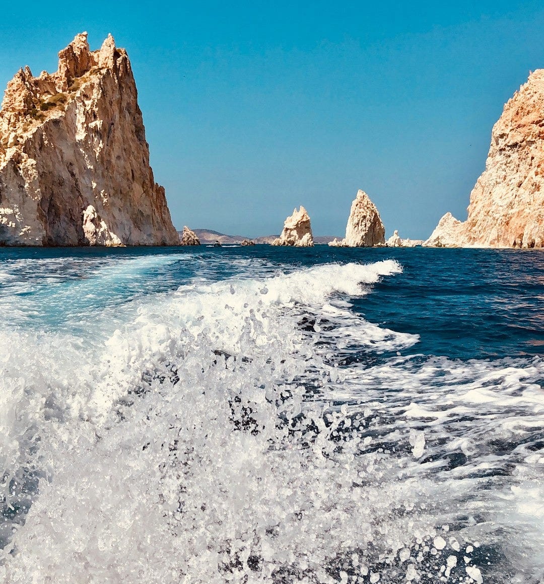 brown rock formation on sea under blue sky during daytime brown rock formation on sea under blue sky during daytime