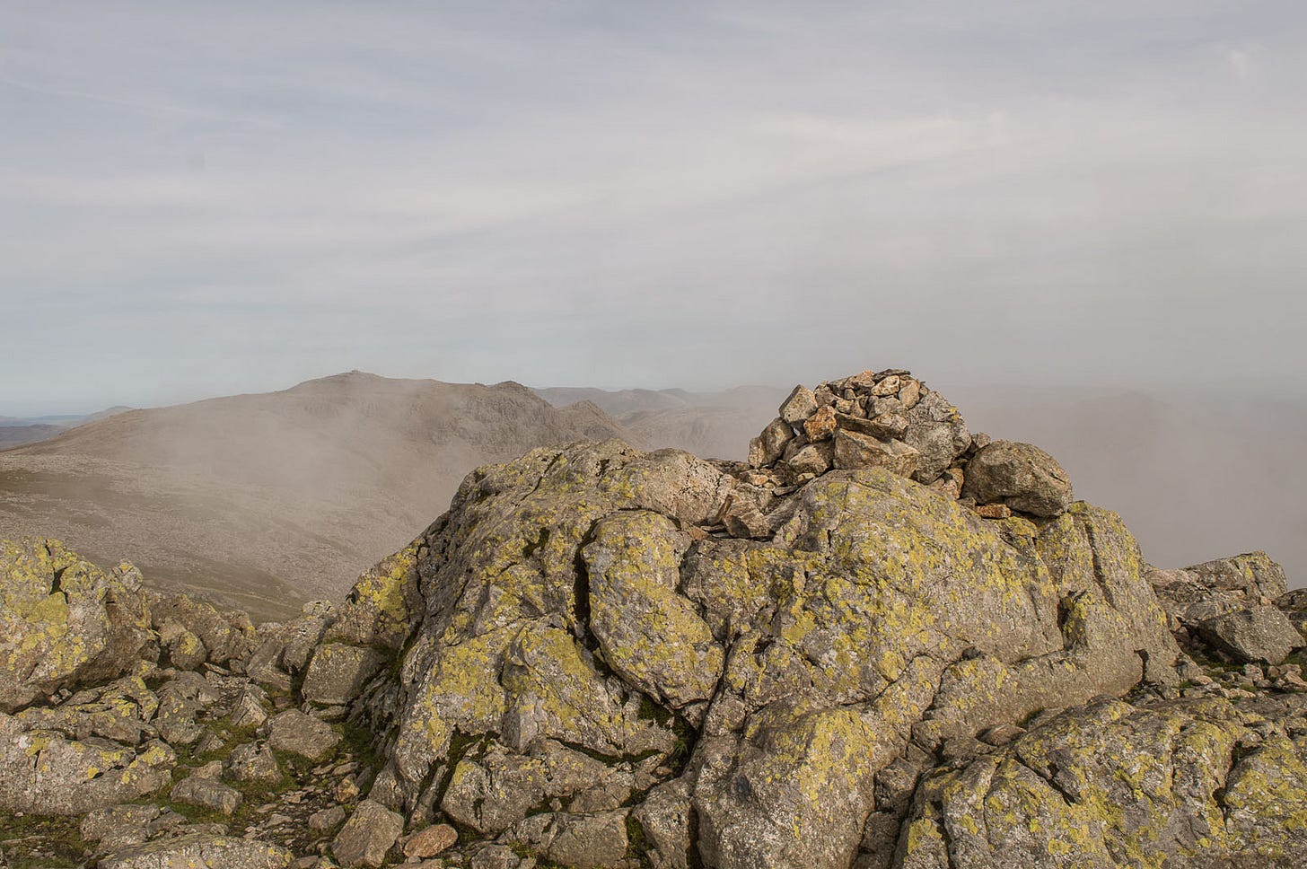 summit cairn, mist, slightly lower mountain behind
