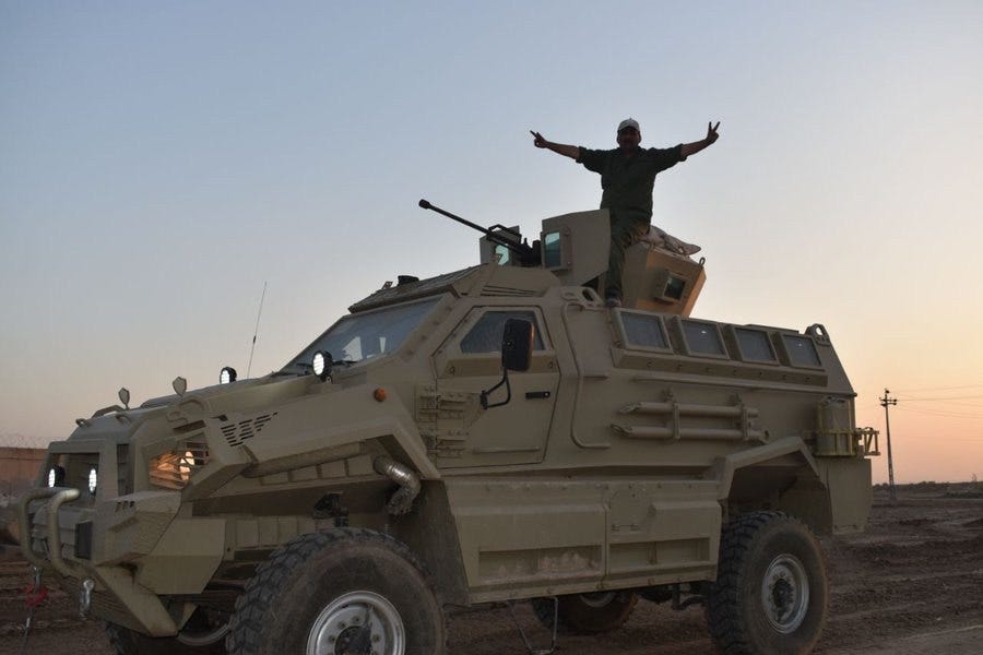 A person standing on top of a military vehicle

Description automatically generated