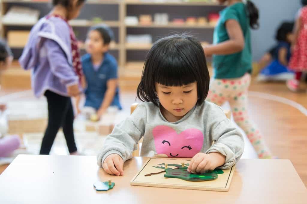 Child exploring body autonomy through self-directed activities at Montessori classroom.