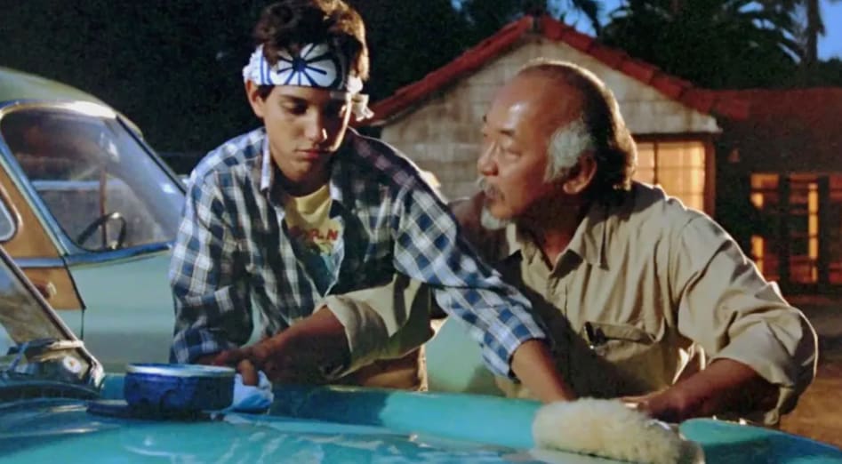 Mr. Myagi showing the Karate Kid how to wax a car