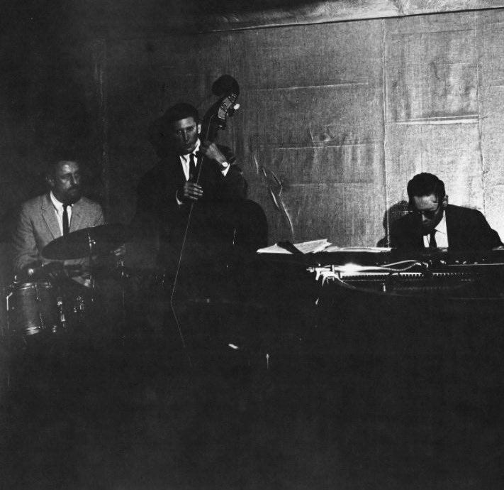 This may contain: black and white photograph of three men in front of a microphone, with one man playing the drums This may contain: black and white photograph of three men in front of a microphone, with one man playing the drums