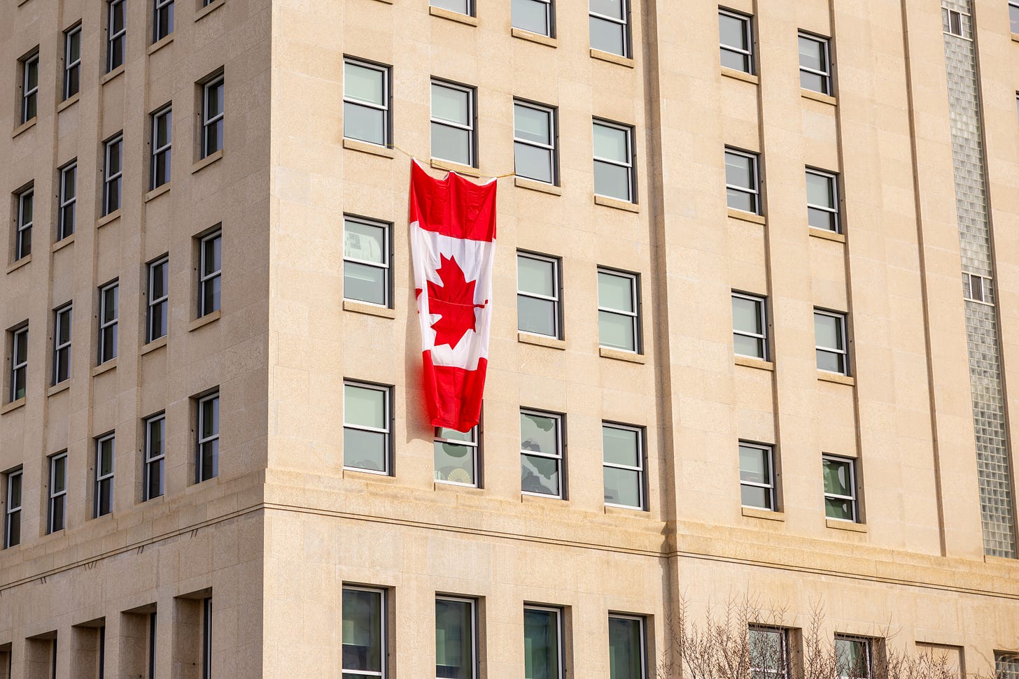 A Canadian flag hangs from the windows of the NDP Caucus offices at the QEII building in Edmonton, facing the Alberta Legislature.