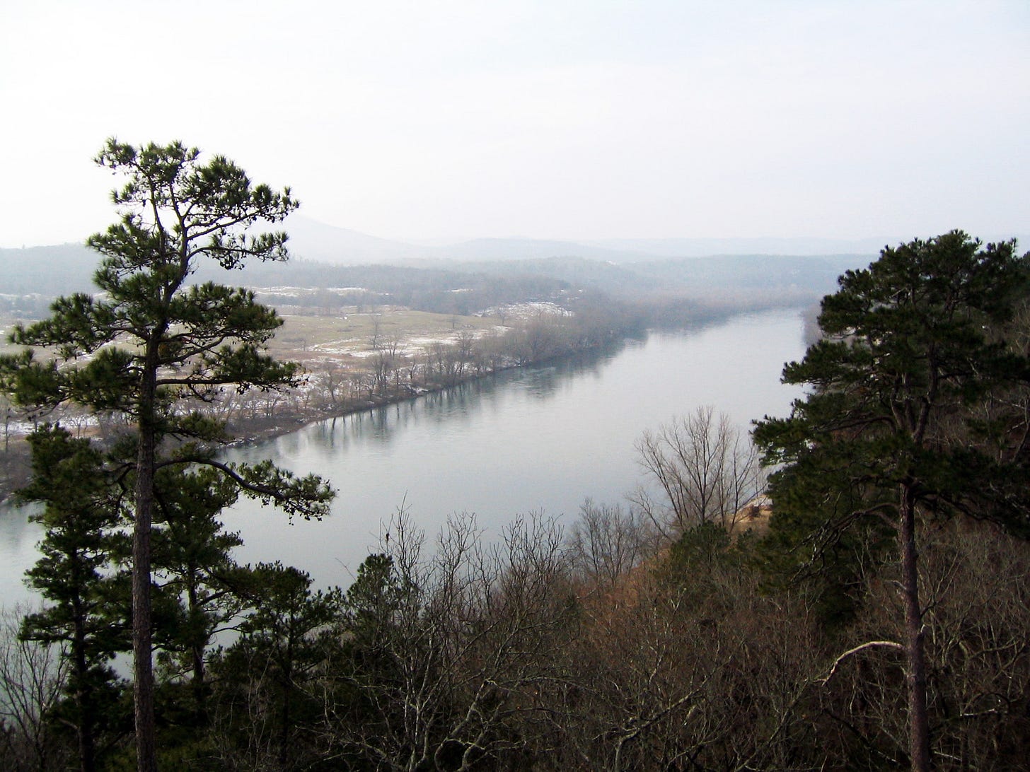 Looking down on a wide and still river in hazy winter light