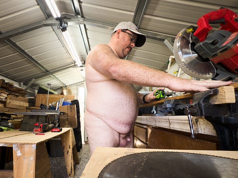 Author Dustin Cox is seen working completely nude in his wood shop. Cutting wood on a saw in the first image. Painting a wood frame black in the second image. Posing with a wood planter box that he built.