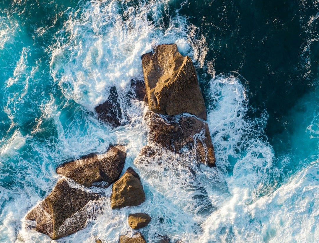 brown rocky mountain beside blue sea water during daytime
