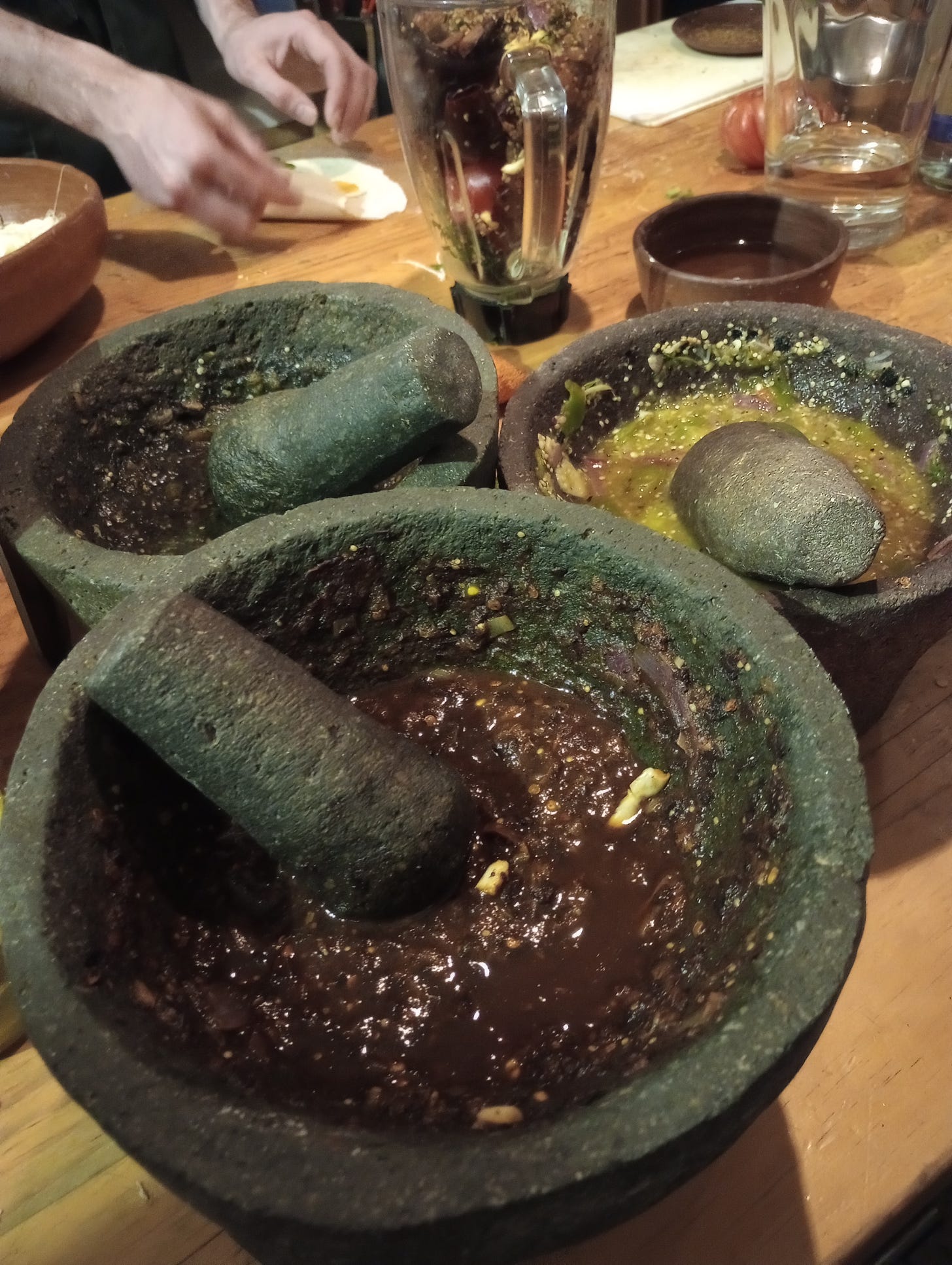 Close-up of salsas and mole in mortar and pestals on a kitchen prep table
