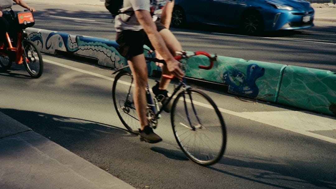 A person rides a bicycle on a sunny street.