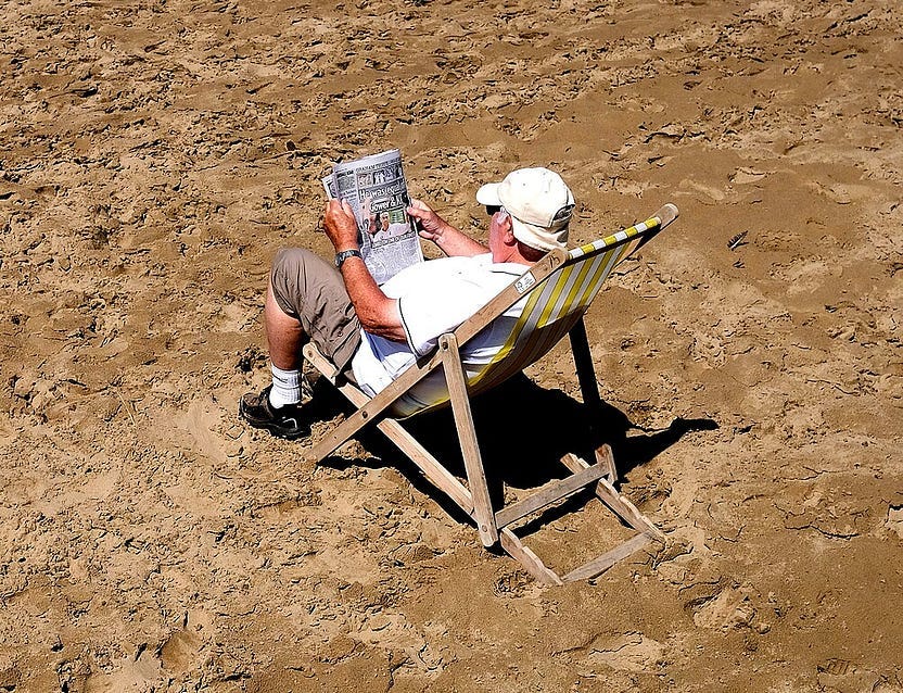 Image of a man reading a paper on a beach Image of a man reading a paper on a beach