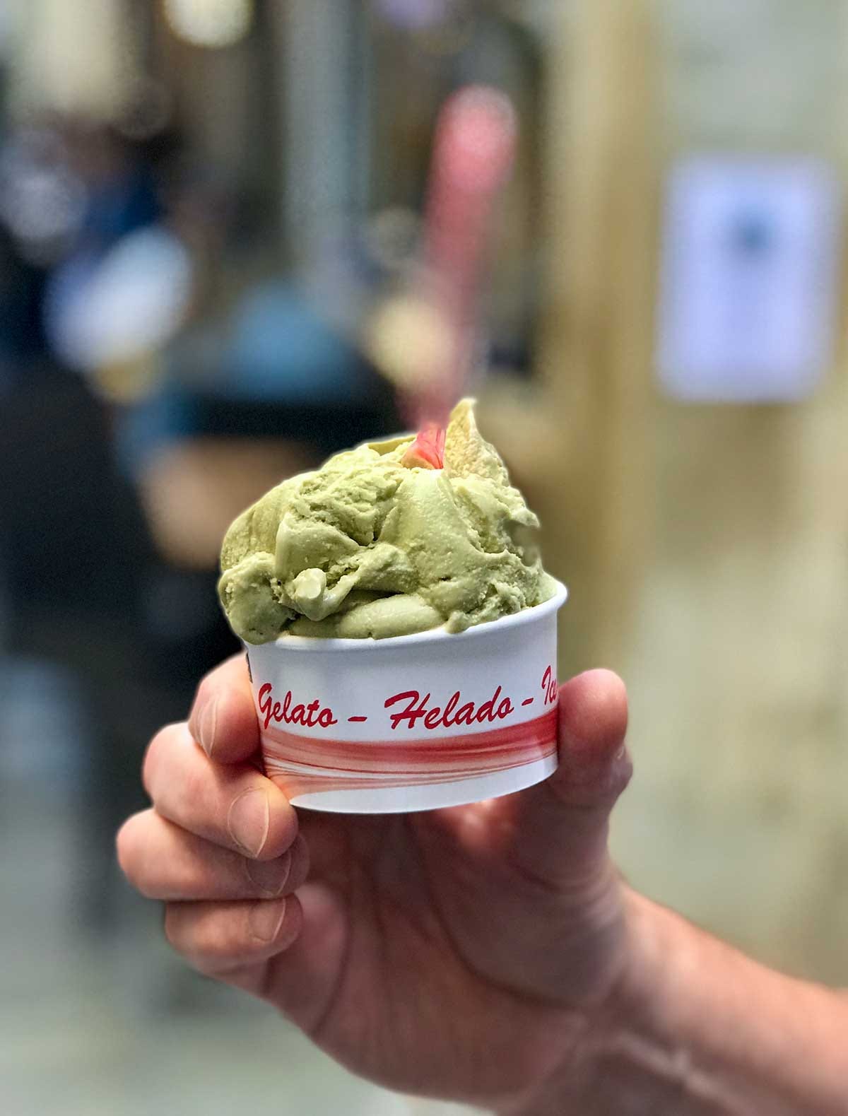 A man's hand holding a cup of pistachio gelato in Venice, Italy A man's hand holding a cup of pistachio gelato in Venice, Italy