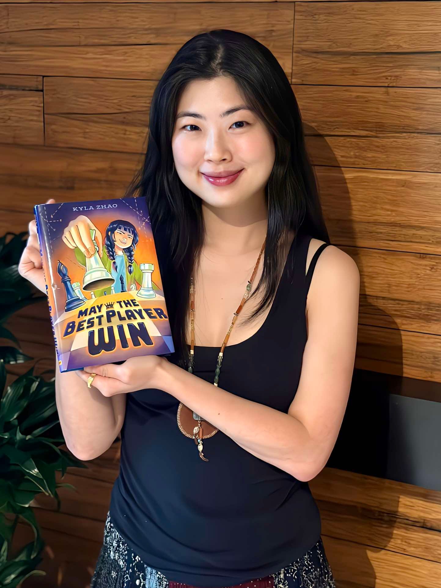 A photo of Kyla Zhao holding her book, May The Best Player Win.