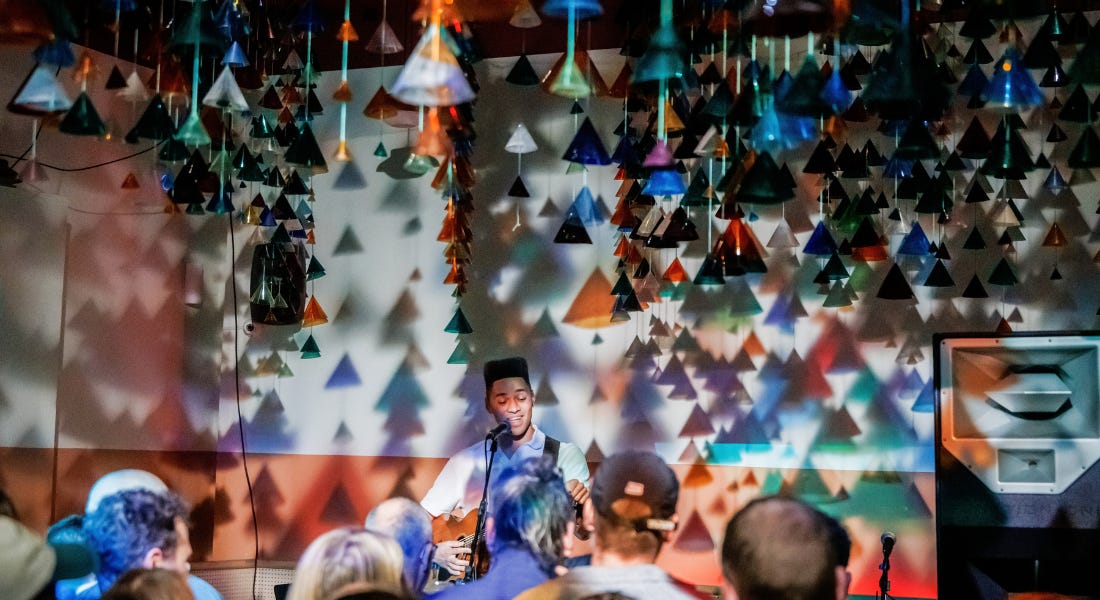 A performer in front of a crowd with triangle decorations hanging down A performer in front of a crowd with triangle decorations hanging down