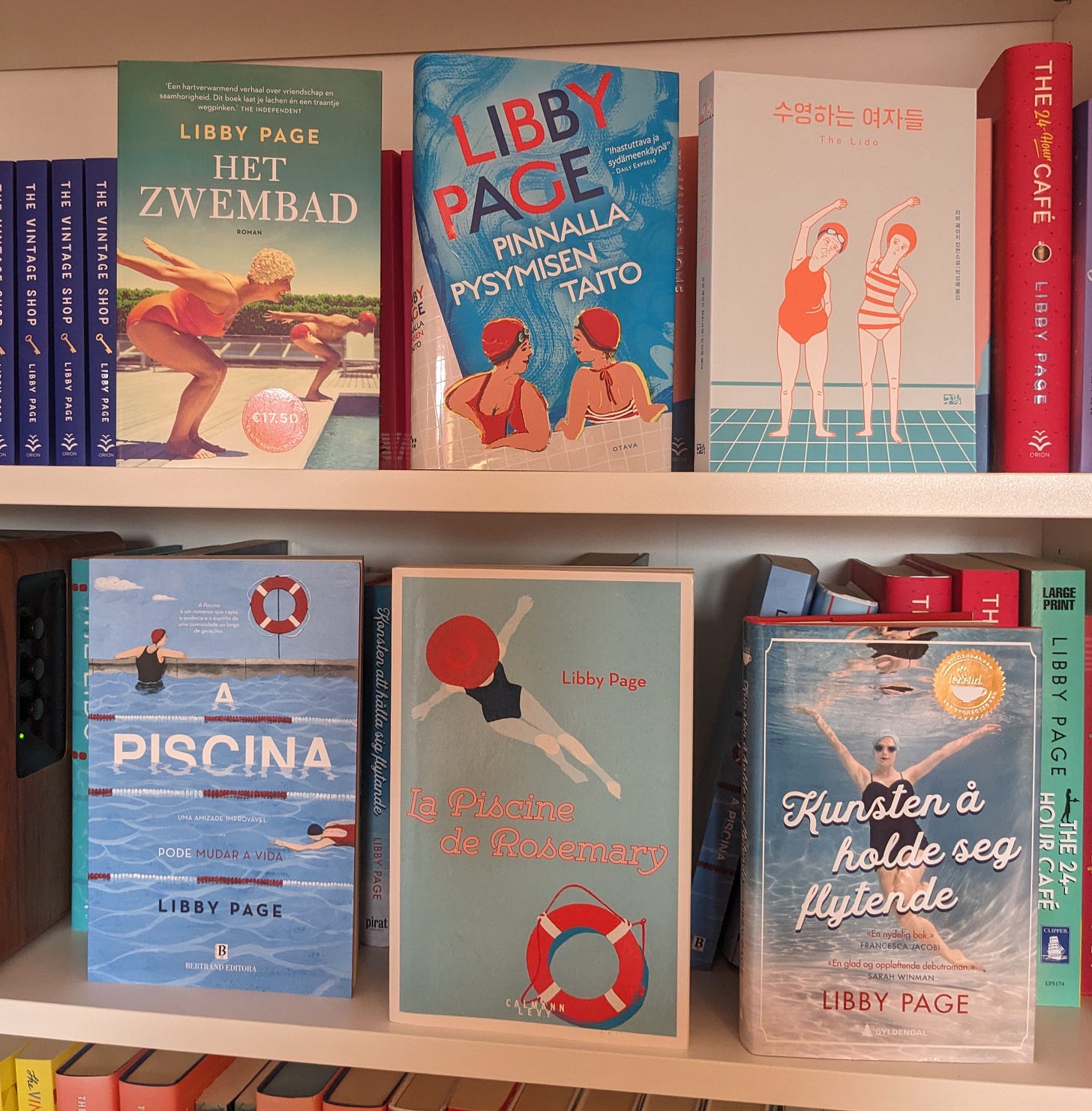 Six foreign editions of The Lido by Libby Page on a shelf, with a variety of different style covers. Some are photographic and others are illustrative.